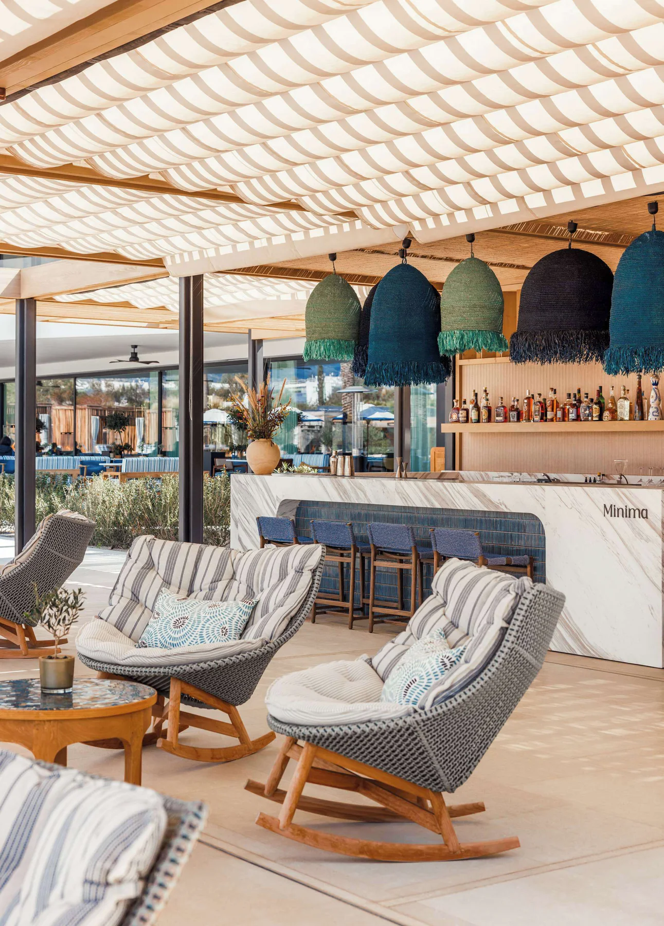 Minima pool bar with woven lights and striped lounge chairs