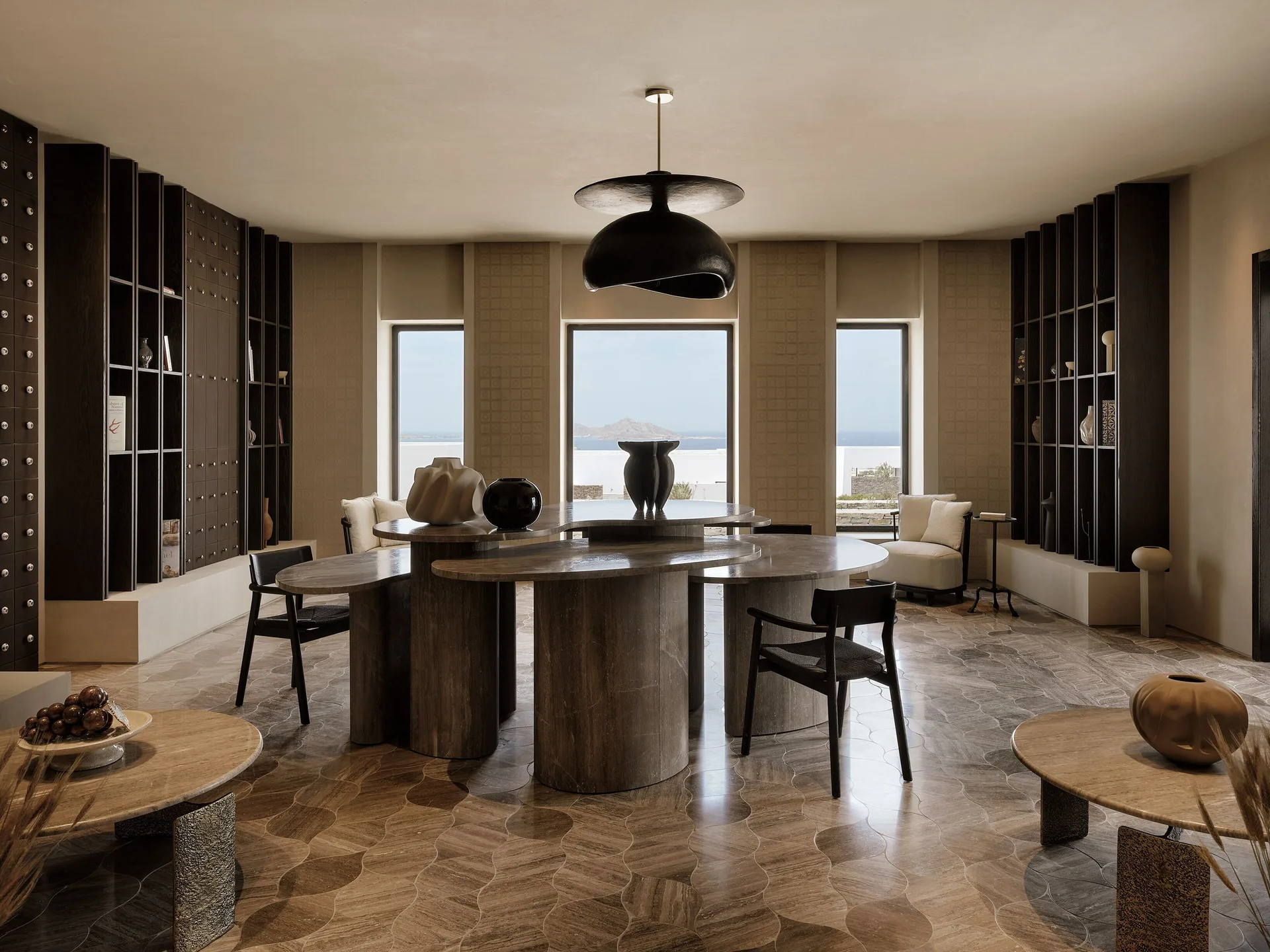 Sculptural tables and dark timber shelving in the sea-facing Oroséa lounge