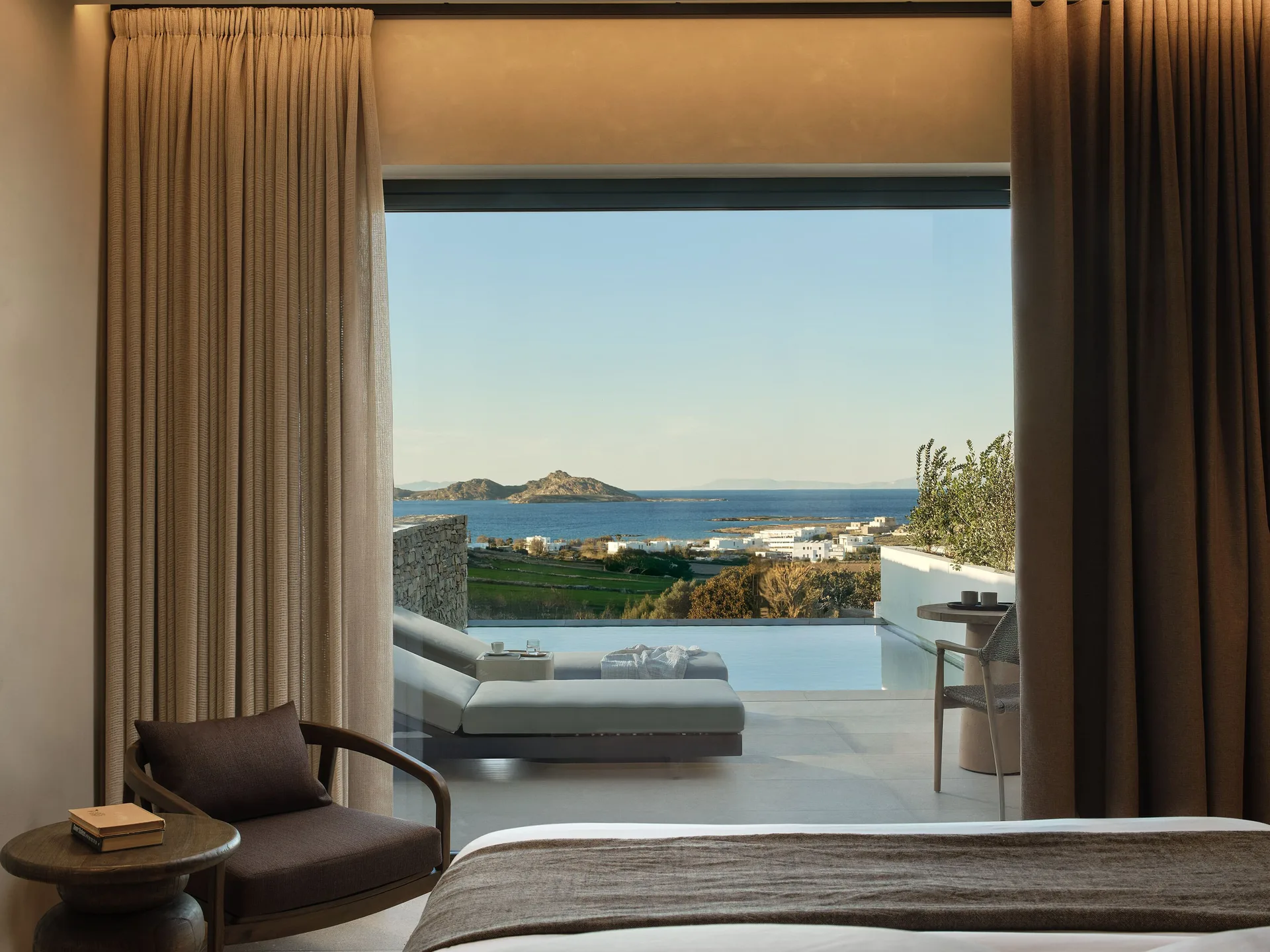 Oroséa bedroom opening towards a private pool and a wide view across the Aegean