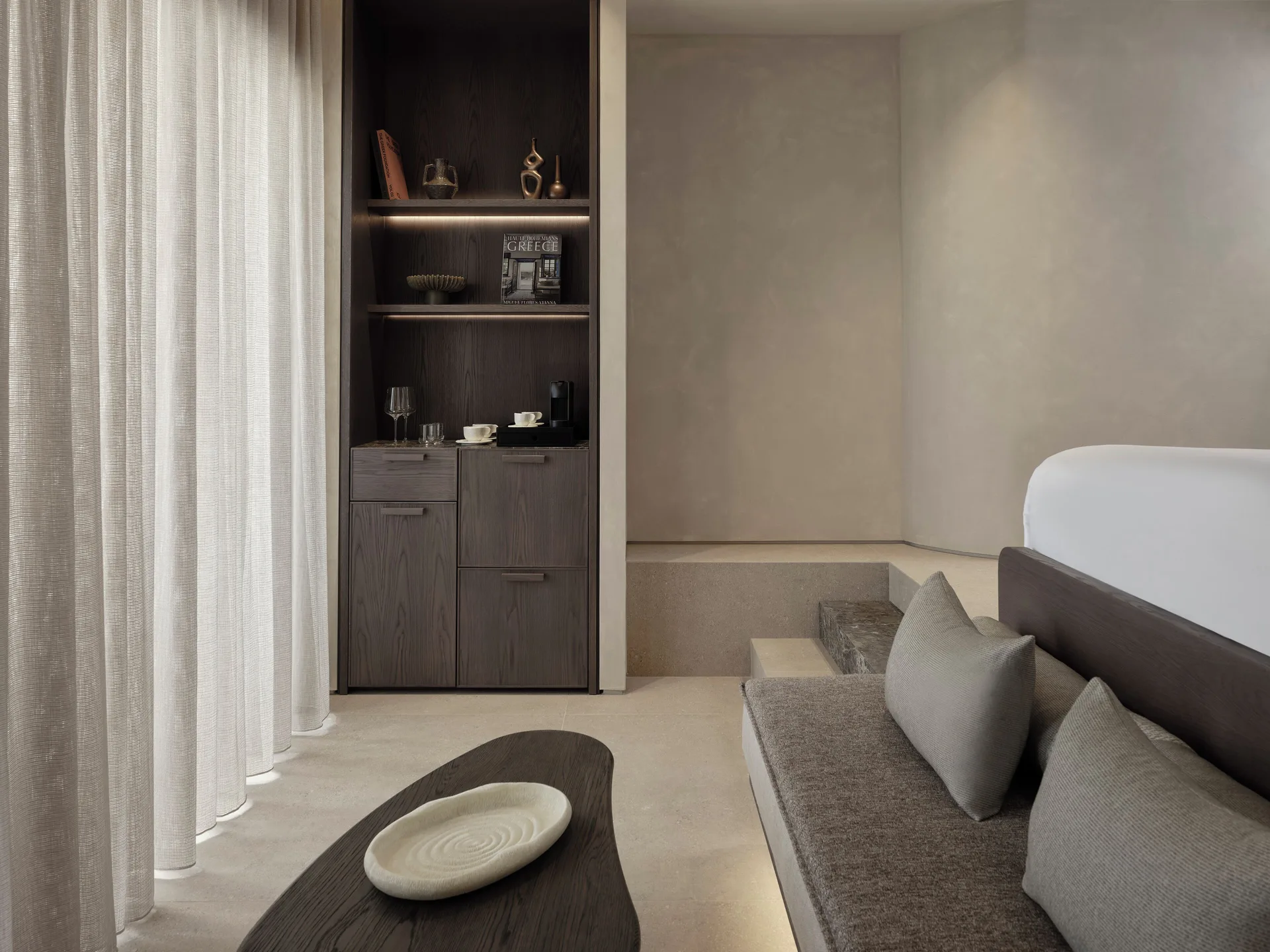 Restrained suite living room with soft neutral plaster, dark timber and built-in seating