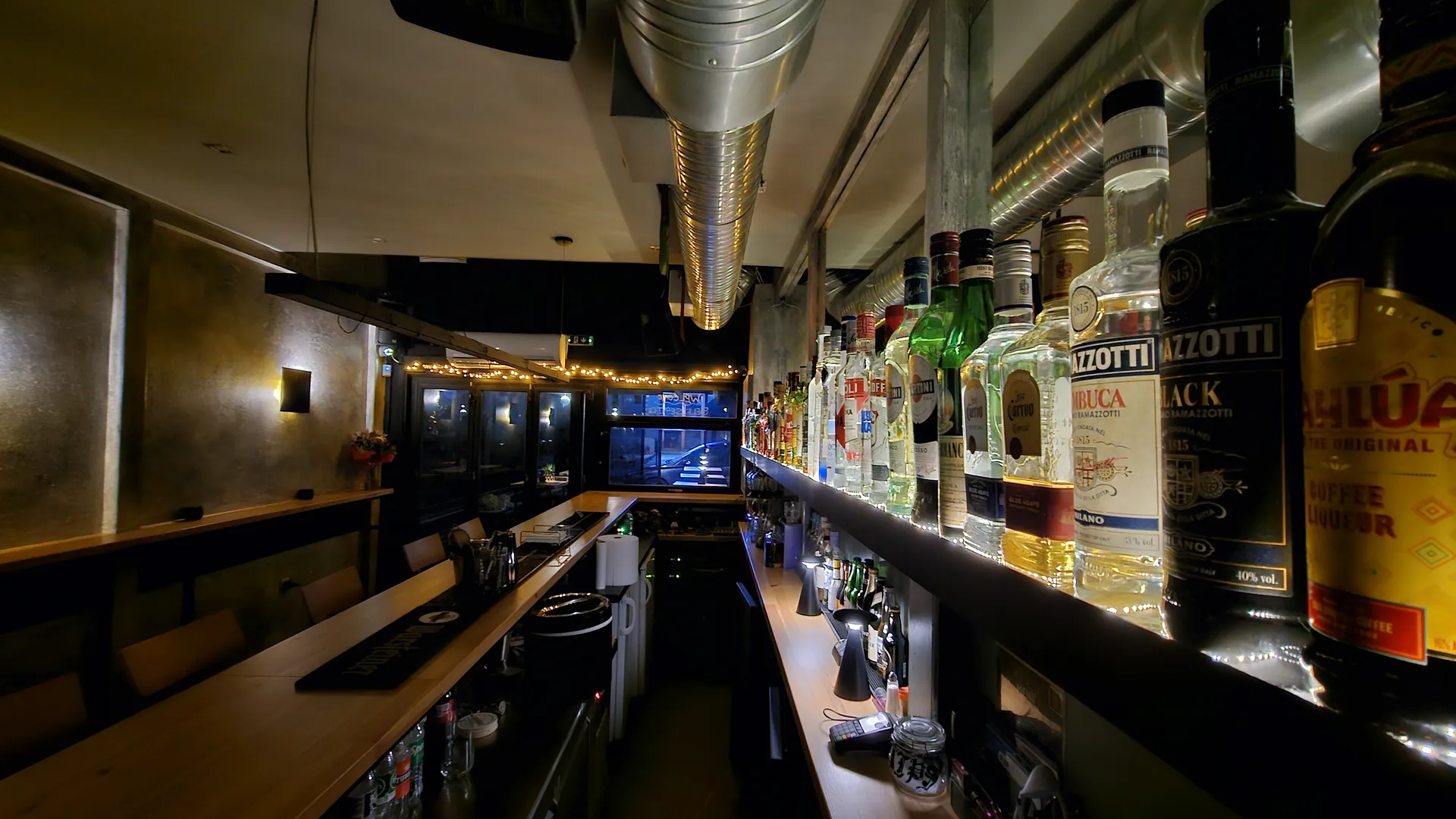 Empty Topan Bar interior with a long timber counter and illuminated spirits shelves